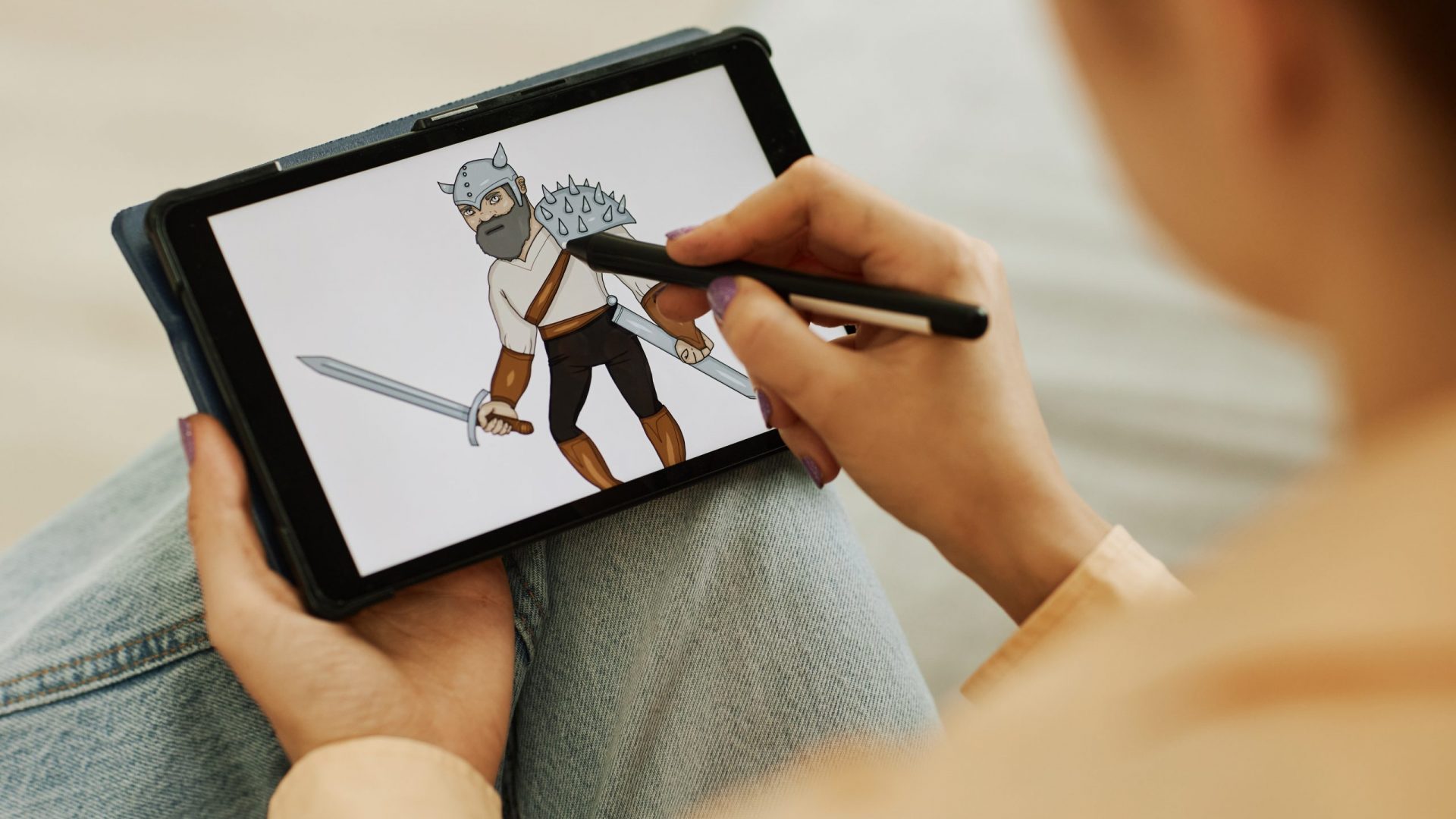 Selective focus on graphic picture of warrior on screen of tablet held by young female digital artist with stylus creating new images
